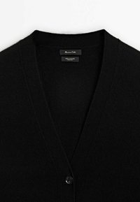 Cardigan noir en cachemire à col en V avec un bouton visible et une étiquette de marque "Massimo Dutti" à l'intérieur du col.