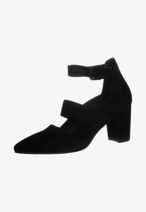 Chaussure à talon aiguille noire en daim avec bout pointu, brides de cheville et talon carré. Comprend deux larges bandes sur le cou-de-pied pour un soutien supplémentaire.