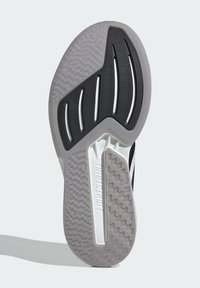 Semelle de chaussure de sport en noir et blanc avec des motifs texturés, incluant des sections lisses et granuleuses, et une marque visible "LIGHTSTRIKE."