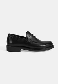Schwarze Lederloafer mit runder Zehenpartie, gestickten Details und einem erhobenen Riemen über dem Vorderfuß. Robuste schwarze Gummisohle.