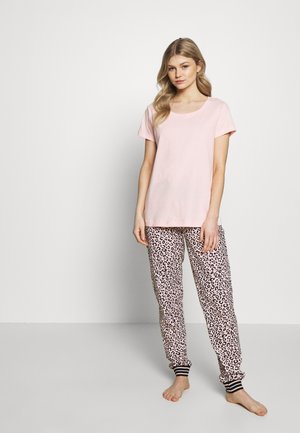 Roze katoenen T-shirt met korte mouwen, gecombineerd met pyjamabroek in luipaardprint. De broek heeft elastische boorden met zwart-witte strepen.