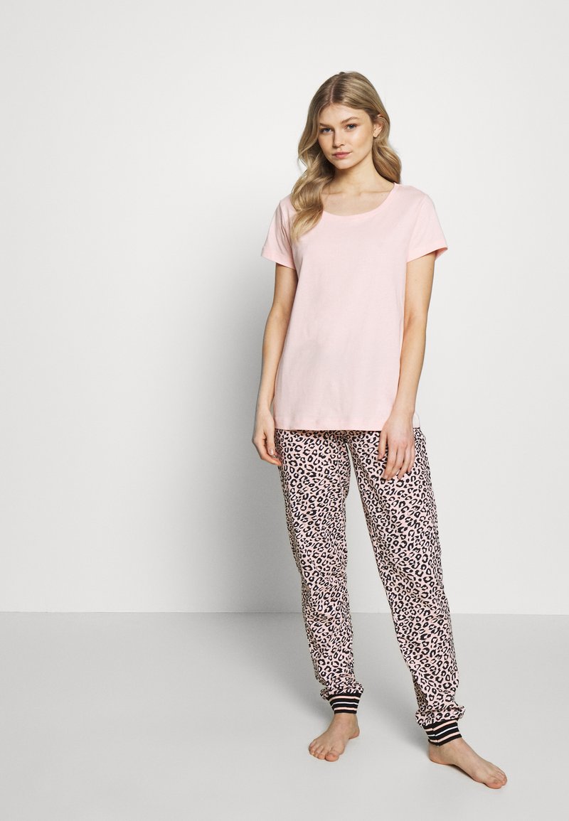 Roze katoenen T-shirt met korte mouwen, gecombineerd met pyjamabroek in luipaardprint. De broek heeft elastische boorden met zwart-witte strepen.