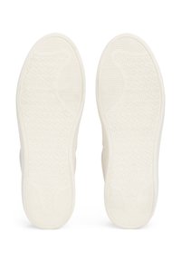 Bílé gumové podrážky tenisek s texturovanými vzory, obsahující drážky a vyvýšené části pro lepší přilnavost a odolnost. Symetrický design, minimalistický vzhled.