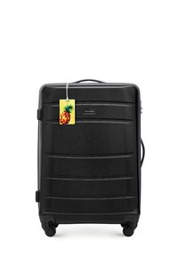 Zwarte harde koffer met een gestructureerd oppervlak, horizontale groeven, een uitschuifbare handgreep, vier wielen en een ananas-thema hangtag.