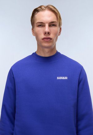 Blue sweatshirt with a crew neck, textured fabric, and a small white logo on the chest. The design is simple and modern.