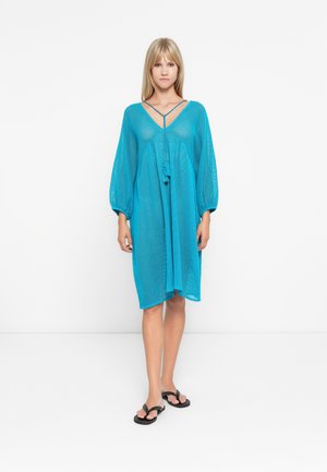 Vestido cubridor ligero en color turquesa con un corte holgado. Cuenta con mangas largas abullonadas, escote en V y un detalle de cordón ajustable en la parte frontal.