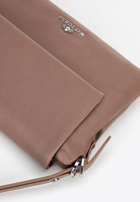 Borsa a tracolla in pelle marrone con superficie liscia, dotata di un logo argentato e di una tracolla regolabile. Chiusura con zip e design a piegatura.