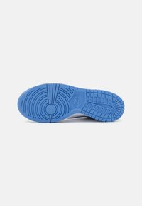 Nike sko såle med fremtredende sirkulært mønster, glatt lys blå gummimateriale og teksturerte grep områder for trekkraft.