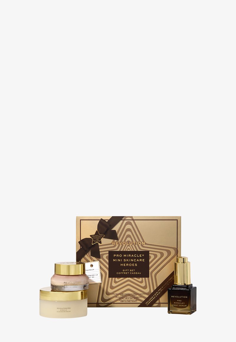Gull og brune Pro Miracle mini hudpleie gaveeske med rensebalsam, fuktighetskrem og nattserumflasker foran en dekorativ boks.