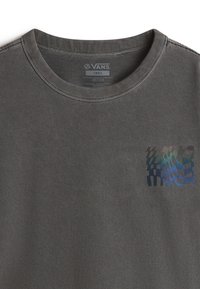Camiseta de algodón gris con cuello redondo y un pequeño patrón abstracto colorido en la parte frontal izquierda. La etiqueta muestra la talla "Pequeña."