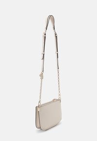 Borsa a tracolla beige con una texture liscia, forma piatta, catena e tracolla regolabile, dotata di chiusura con zip e minimi accenti hardware.