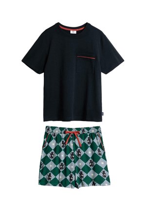 Chemise noire à manches courtes avec une bordure rouge sur la poche poitrine, portée avec un short à carreaux verts et gris orné de motifs de chats noirs et d'un cordon rouge.
