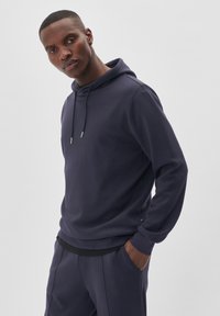 Sudadera con capucha azul marino en un material suave, con cordón y bolsillos laterales. Textura lisa con un diseño de corte relajado.