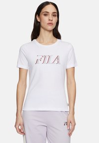 Witte katoenen t-shirt met korte mouwen, voorzien van een opvallend rood en grijs "FILA"-logo op de voorkant. Eenvoudig, strak ontwerp. Geen patronen of accenten.
