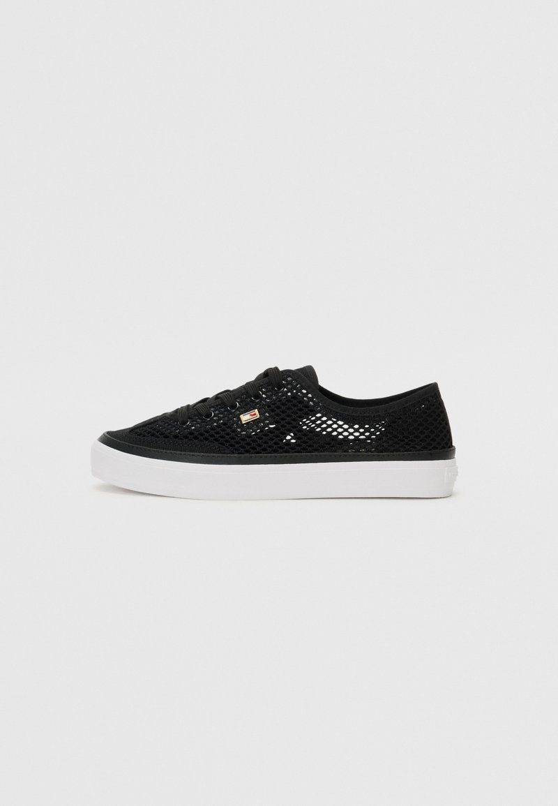 Baskets basses en mesh noir avec semelle en caoutchouc blanche et lacets noirs, vues de profil sur un fond uni.
