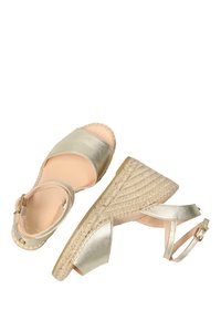 Alpargatas de cuña en oro metálico, con punta abierta, tira al tobillo y tacón de yute trenzado. Textura suave y suela resistente.