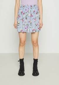 Saia floral azul clara com flores rosas e amarelas, com cintura elástica e design plissado; combinada com botas de combate pretas com atacadores.