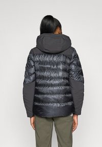 Jachetă puffer neagră cu glugă ajustată, design cusut, și texturi contrastante mate și lucioase; prezintă manșete elastice și tiv ajustabil.