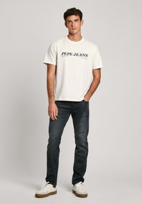 Bela bombažna majica slogom "PEPE JEANS", v kombinaciji s temnimi denim hlačami in belimi supergami s svetlimi podrobnostmi. Preprost dizajn in kroj.