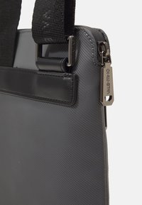 Zaino grigio testurizzato realizzato in materiale sintetico, con spallacci neri e tirazip in argento con dettaglio del logo.