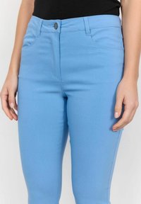 Blauwe denim skinny jeans met een gladde textuur, voorzien van een voorste knoopsluiting, riemlussen en twee voorzakken.