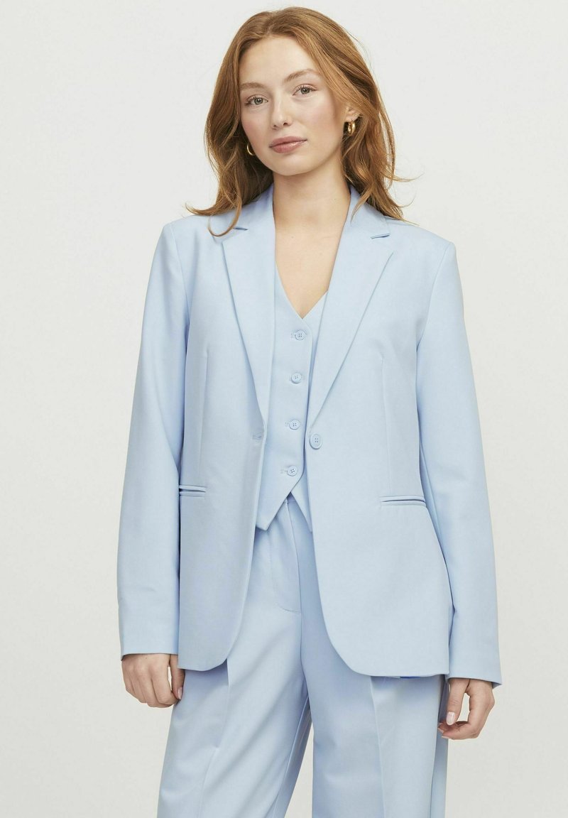 Lichtblauw pak met een op maat gemaakte blazer en bijpassend vest. Gladde stof, enkele rij knopen, met twee voorzakken en knoopsluitingen.