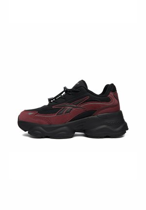 Czarno-ciemnoczerwony sportowy sneaker z grubą czarną podeszwą, zapięciem na sznurowadła i logo Reebok po boku.