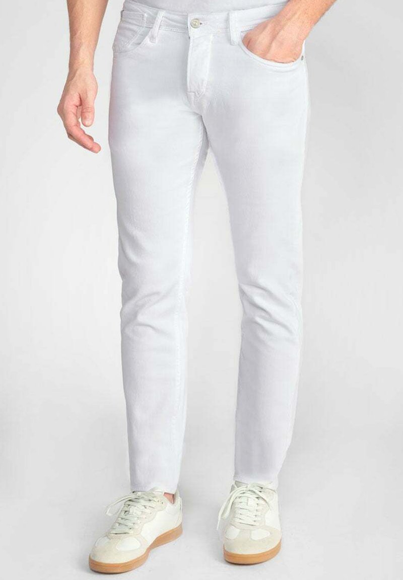Witte denim jeans met een slim fit, vijf-pocket ontwerp en subtiele stiksels, gecombineerd met lichtgekleurde sneakers.