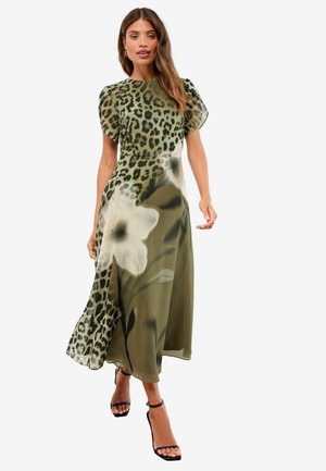 Maxikleid aus leichtem Stoff mit olivgrünem Grund, Leopardenmuster und weißen Blumenmotiven. Es hat kurzärmelige Cap-Ärmel und eine fließende Silhouette.
