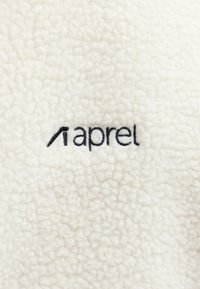 Tissu en polaire blanc texturé avec logo "aprel" brodé en noir centré.