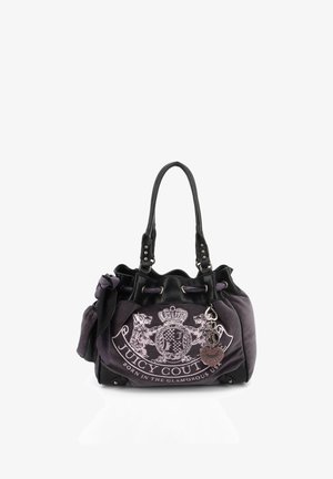 Dunkellila Juicy Couture Handtasche mit schwarzen Griffen, vorderem Wappenlogo und herzförmigem Anhänger vor weißem Hintergrund.