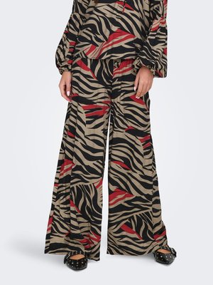 Bukser med vide ben og matching top med sort, beige og rød abstrakt zebra print, båret med sorte flade sko med nitter.