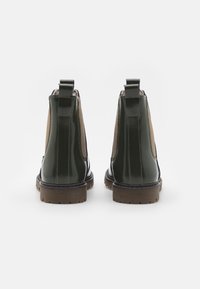 Botines de tobillo de charol verde con paneles de ante marrón claro, inserciones laterales elásticas y suelas de goma texturizadas. Incluyen cintas traseras para tirar.