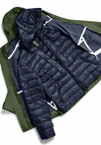 Granatowa kurtka puchowa z poziomymi przeszyciami i kieszeniami na zamek, noszona pod oliwkowo-zielonym wodoodpornym płaszczem z kapturem i elastycznymi akcentami.