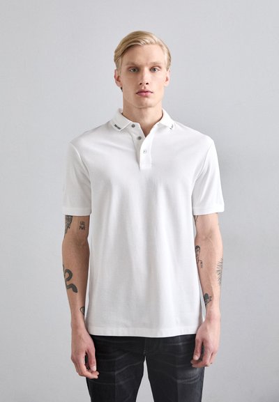 Polo bianco con colletto tradizionale, dotato di una patta con bottoni, maniche corte e una texture in cotone liscia.