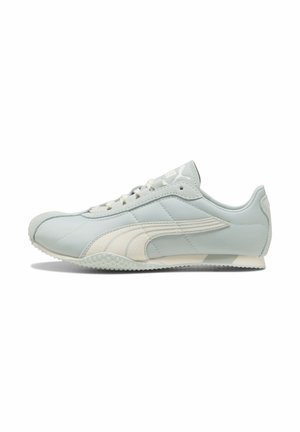 Lysegrå lavtop sneaker med hvid Puma-logo stribe, snørebånd foran, tekstureret sål og ruskindstropper på tå og hæl.