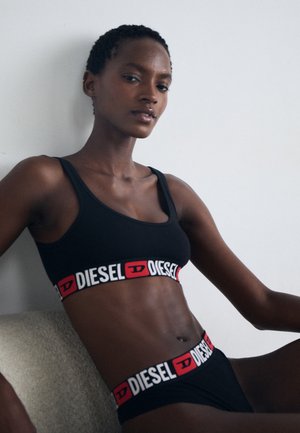 Zwarte sportbeha en bijpassende slips met een gedurfde witte en rode Diesel-logo op de elastische band. Glad, rekbaar doek en eenvoudig ontwerp.