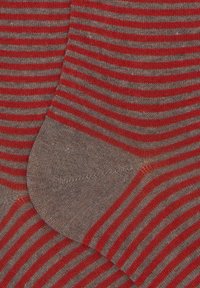 Calze a righe rosse e grigie con una texture morbida e lavorata a maglia. Il motivo presenta righe alternate, con le punte e i talloni di un grigio uniforme.