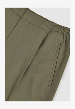 Pantaloni verde oliva con tessuto testurizzato. Presentano una vita elastica e tasche laterali, con linee pulite e dettagli di cucitura minimal.