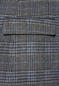 Szary materiał w kratkę z niebieskimi akcentami, charakteryzujący się subtelną teksturą i górną kieszenią. Wzór składa się z przeplatanych ciemnych i jasnych nitek.