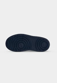 Σόλα μαύρου αθλητικού παπουτσιού Nike με κυκλικά σχέδια στο πέλμα και το λογότυπο Nike Swoosh στο κέντρο της σόλας.