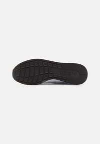 Semelle de chaussure de sport PUMA, dotée d'un motif en caoutchouc noir texturé avec un logo. Des rainures profondes améliorent l'adhérence et la durabilité.