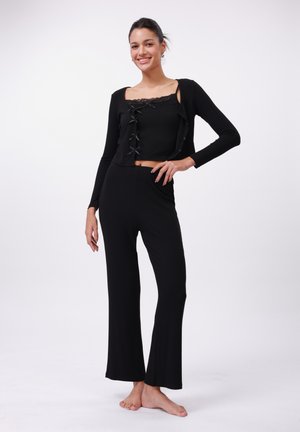 Black ribbed knit set featuring a cropped top with lace trim and a button-front design, paired with flared pants. Soft texture, relaxed fit.