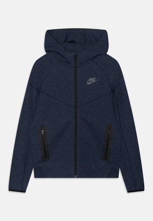 Námořnická modrá mikina na zip s kapucí, vyrobená z hladkého materiálu, s černým zipem a dvěma postranními kapsami na zip. Logo Nike na hrudi.