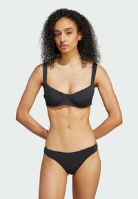 Černý bikiny set s pevným podprsenkovým topem a širokými ramínky, doplněný o nízké kalhotky. Hladký povrch a minimalistický design.