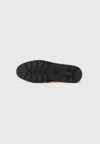 Semelle de chaussure en caoutchouc noir avec des profondeurs de sculpture et un motif texturé. Présente le nom de la marque "PINKO" en relief près du talon.