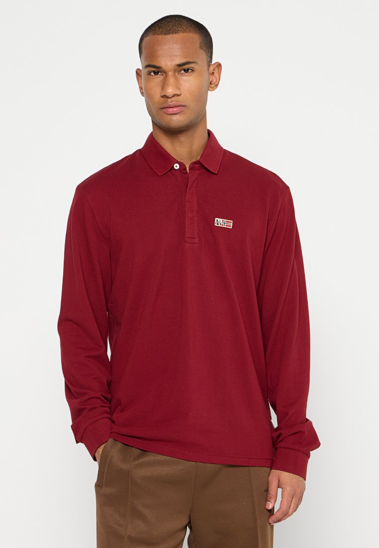 Bordowa koszula polo z długim rękawem z bawełny, z kołnierzykiem, zapięciem na dwie guziki oraz małą naszywką z wyszywanym elementem wzorniczym.