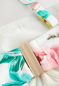 Top bikini con stampa floreale in verde, rosa e bianco; presenta una chiusura color oro e spalline testurizzate per una vestibilità sicura.