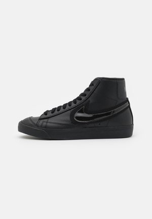 Černé vysoké tenisky s texturovaným koženým svrškem, plochou černou podešví a kontrastním lesklým černým logem Swoosh na vnější straně.