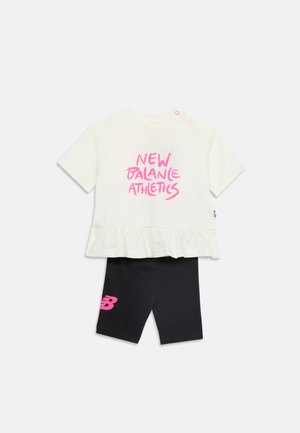 Top alb cu mâneci scurte, cu text roz "New Balance Athletics" și tiv cu volănașe, asortat cu colanți negri până la genunchi, cu logo roz "NB".